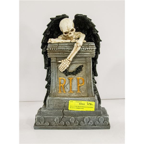 SKELETON WITH WINGS STANDING BEHIND TOMBSTONE