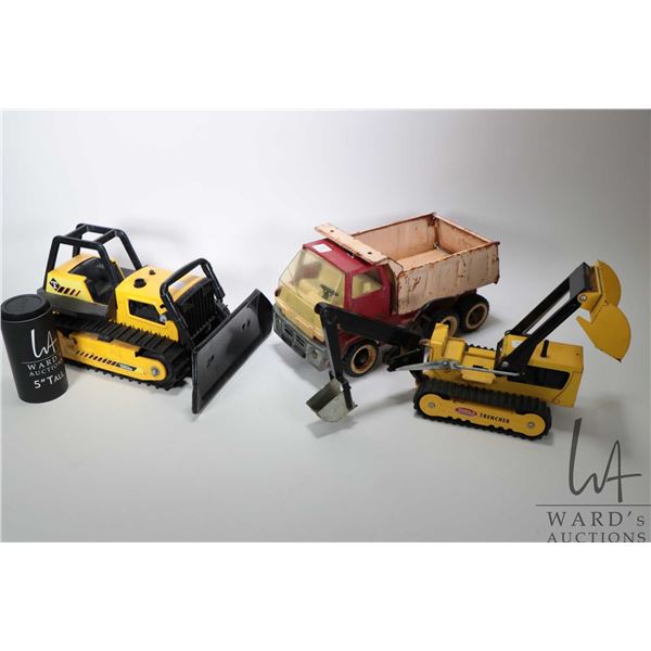 Three vintage Tonka pressed steel toys including a back hoe, dozer and a dump truck