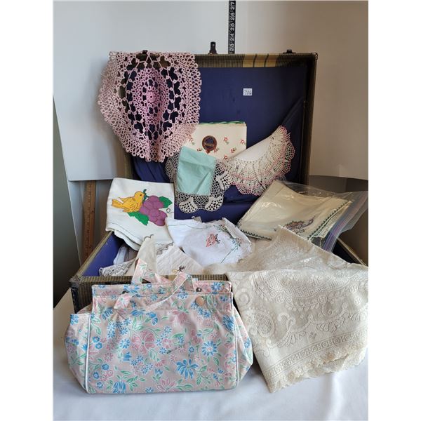 Old worn suitcase full of vintage linens, doilies, table clothes, shelf paper, toiletry bag & more.