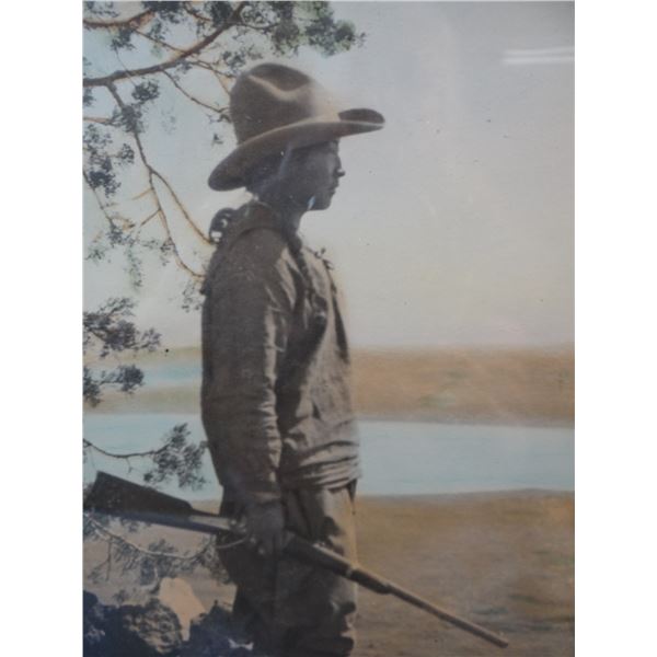 Framed hand tinted old photo of a young man with a rifle standing next to a tree, 10  x 1 6 