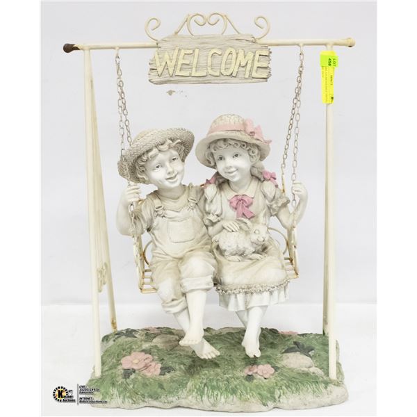 BOY + GIRL ON MOVEABLE SWING, WELCOME SIGN