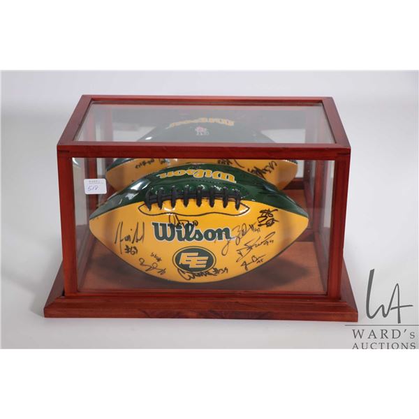 Team signed green and gold Edmonton Eskimos football in display case