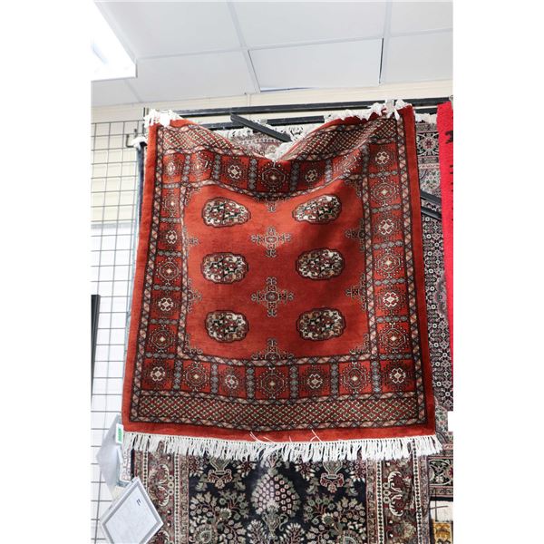 Small square wool area carpet with deep brick background, geometric design, fringed edge and highlig