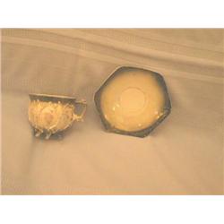 Hexagon shaped cup & saucer in white porcelain decorated with metallic green & silver dating back ap