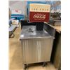 Image 2 : MOBILE STAINLESS STEEL PREP TABLE WITH VINTAGE COCA COLA DISPENSER PROP APPROX 36"X36"X24"