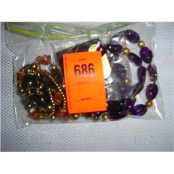 2 necklaces: 1 ornate purple glass with gold-tone accents, 36"; 1 agate with gold-tone bead accents,