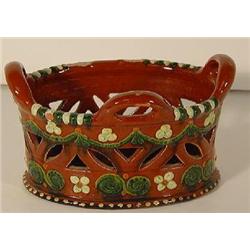 AN OVAL PENNSYLVANIA DUTCH REDWARE BASKET