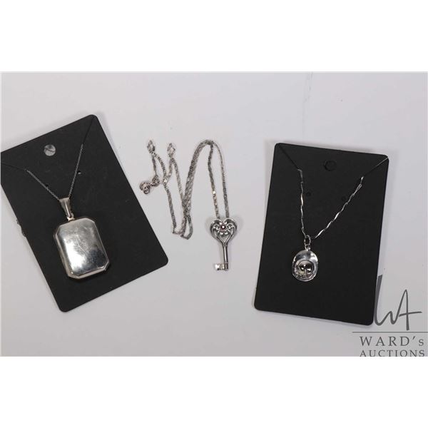 Three pieces of sterling silver jewellery including 16" necklace with key pendant, helmet pendant on