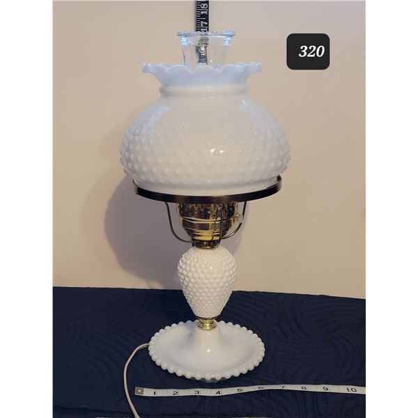 White hobnail milk glass lamp with hurricane shade inside.