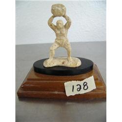 Bone carving of a cave man throwing a rock mounted on wood base ()