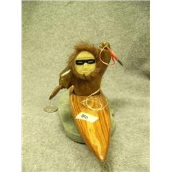 Soapstone kayaker/hunter with ivory face and baleen snow goggles, in wood kayak mounted on soapstone