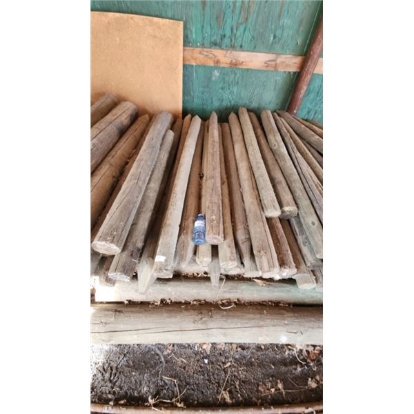 Large pile of round fence post stakes