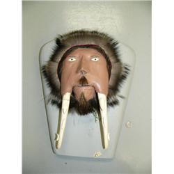 Walrus head carved into man's face with carved animal tusks, inset ivory eyes and driftwood pupils, 