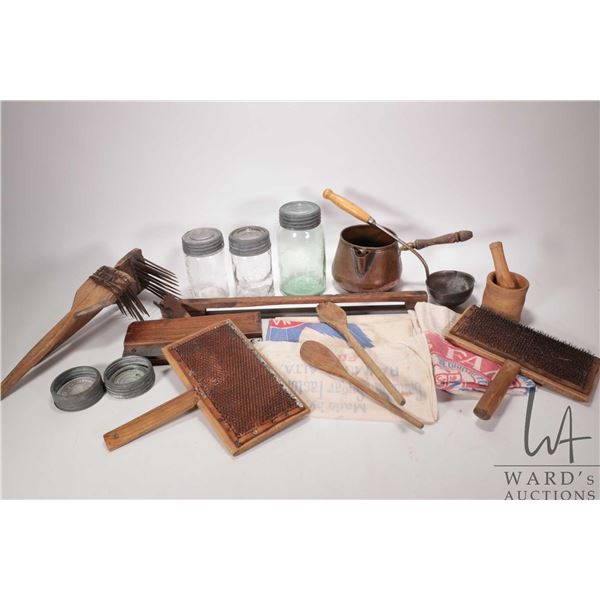 Selection of prairie household items including wool carders, set of berry pickers, wooden saw, seale