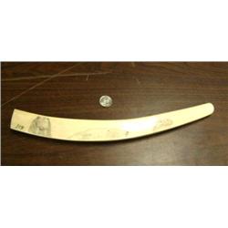Ivory scrimshawed tusk on all four sides: walrus, polar bear face, seal, mukluk, mitten, seal, tool,
