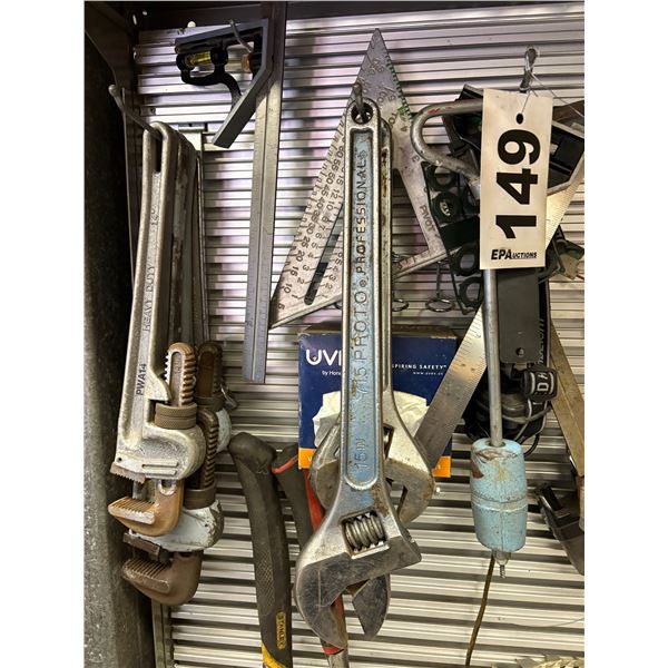 Various tools hanging on the wall. Pipe wrenches, crescent wrenches, squares, hack saws etc.