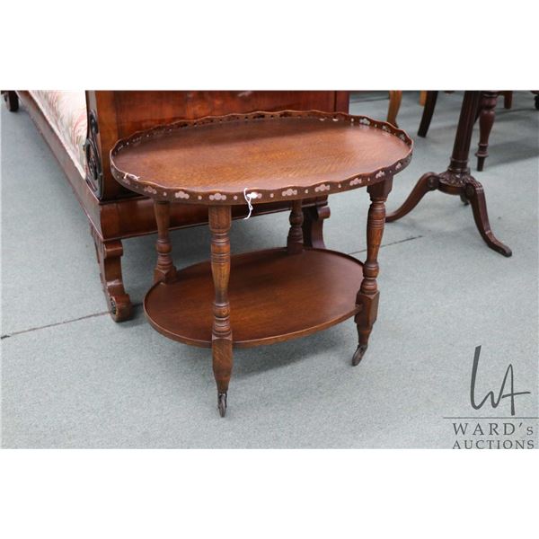 Antique quarter cut oak, two tier occasional table with sculpted fretwork galley on castor, 22" H X 
