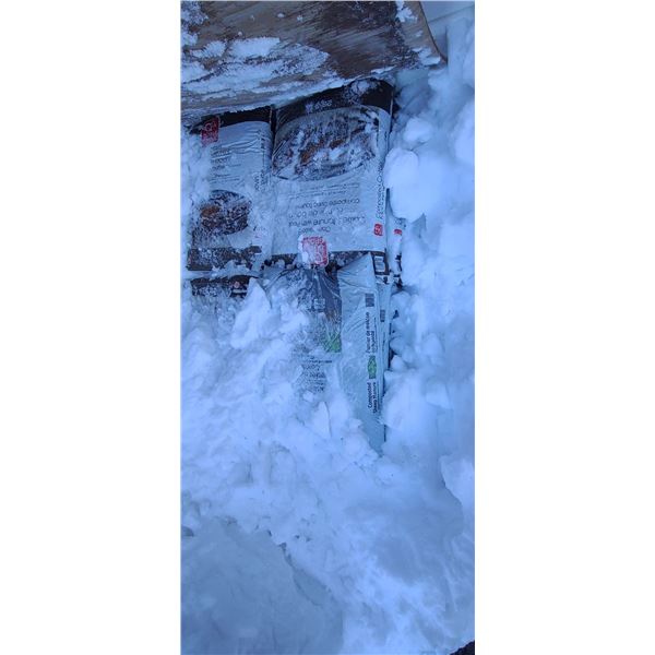 PILE OF STEER MANURE BAGS UNDER PLYWOOD
