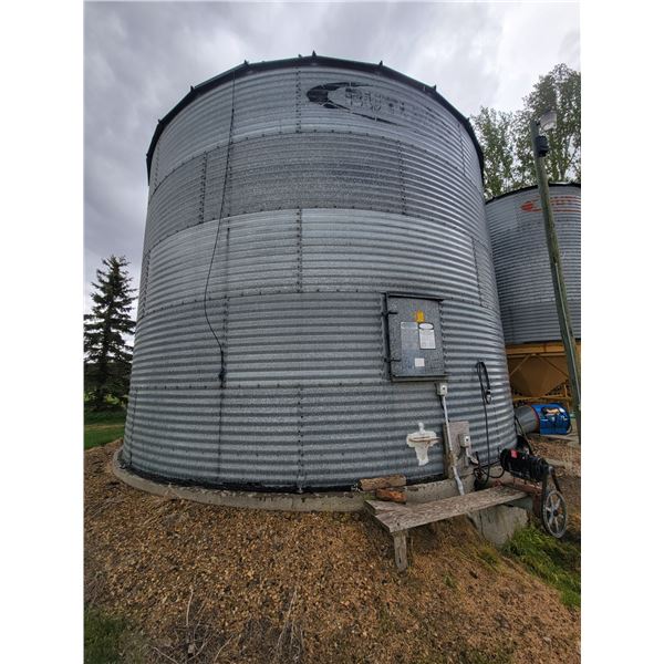 Butler 5-ring grain bin mounted on concrete, 10,000 Bu c/w auger system & motor. Approx. 24 ft dia.,