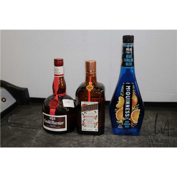 Three assorted bottles of liquor including one McGuiness Blue Curacao 750ml / 15% ABV, one GrandMarn