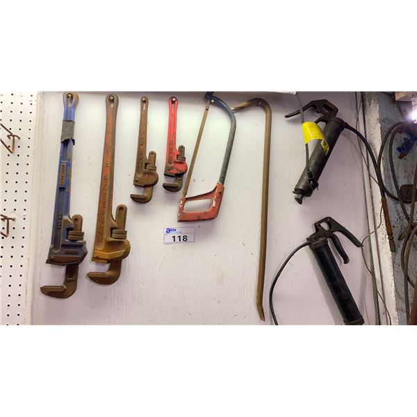 GROUP LOT OF TOOLS ON WALL. 4 PIPE WRENCHES, CROW BAR, GREASE GUNS