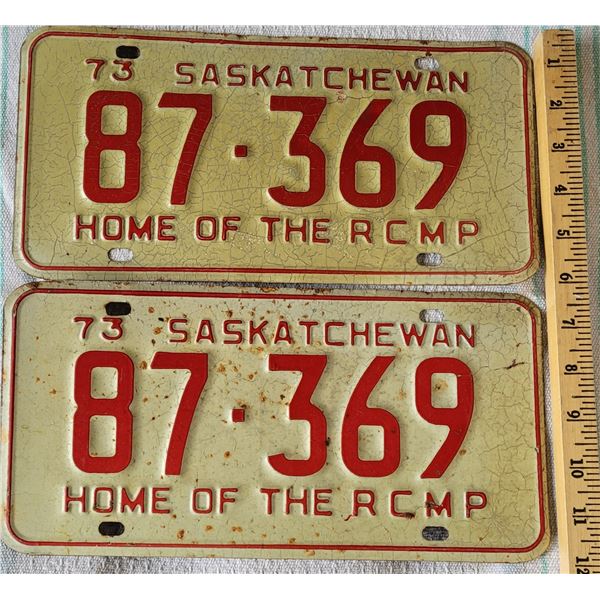 Set of two 73 HOME OF THE RCMP Saskatchewan license plates, red print on crackled cream background, 