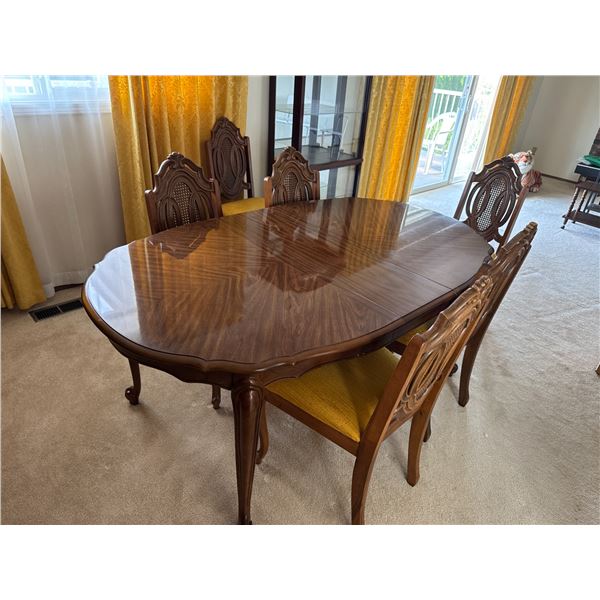 Dining table with six chairs pictured with leaf in it