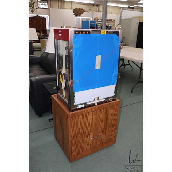 Cretors popcorn machine 27" H X 20" W X 14" D, in unused condition, sitting on 23" H shop made two d