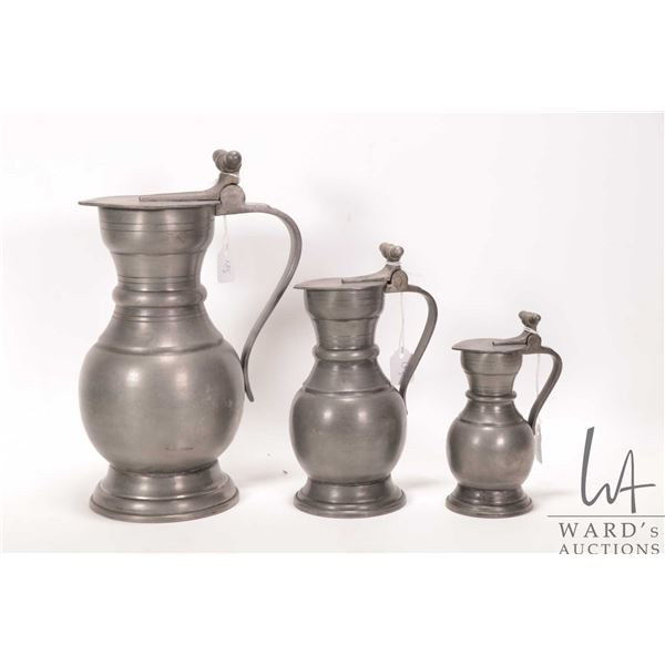 Three antique graduated pewter lidded ewers, 5" to 10"