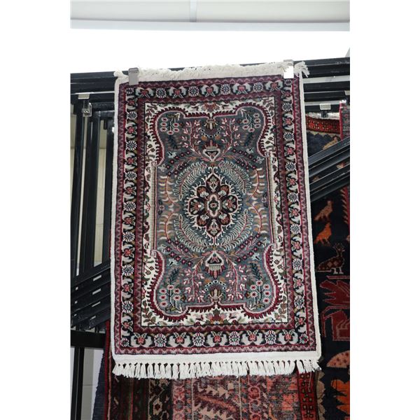 Small fringed scatter rug with center medallion, floral design and highlights of grey, brick and sag