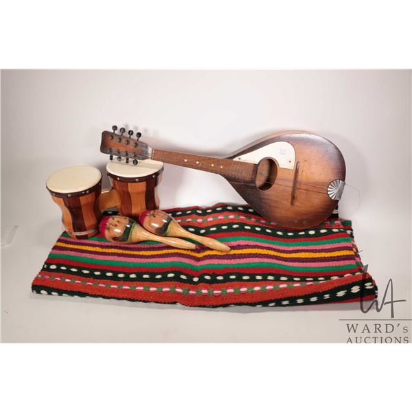 Vintage flat-back mandolin, a small pair of bongo drums, maracas and a woven colourful throw