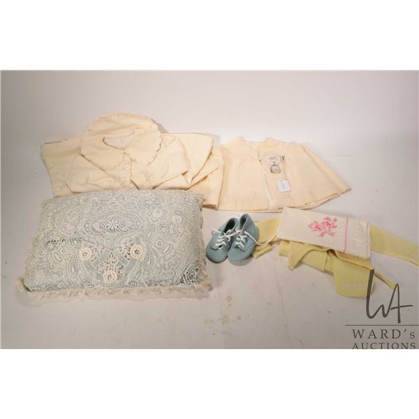 Small selection of baby items including lace pillow, wool coats, silver baby rattle and a sterling s