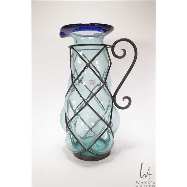 Large hand blown glass pitcher encased in wrought iron galley. Measures 17" high . Note: Not availab