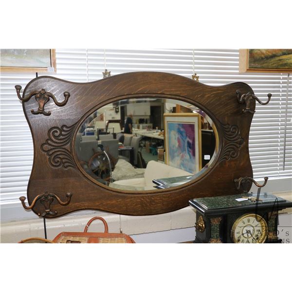 Antique quarter cut oak wall mirror with original cast hooks, overall dimensions 24" H X 40" W. Note