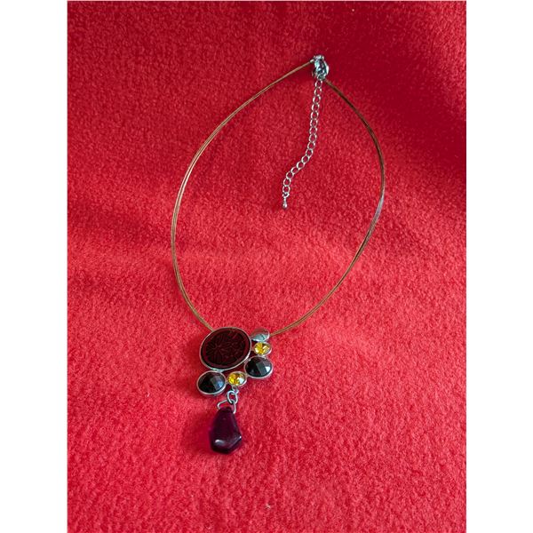 Modern metal pendant necklace on a cable chain with a cluster of black and amber-colored accents.