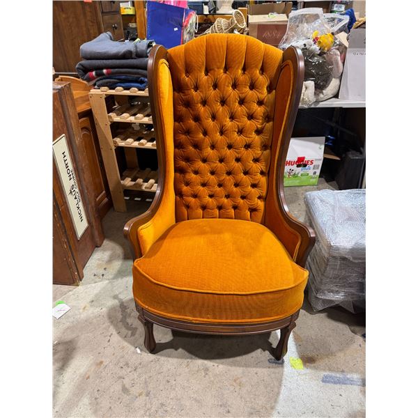 vintage tufted wingback chair with orange velvet upholstery and a dark wood frame.