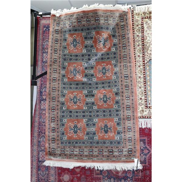 Small wool are carpet with geometric patter, taupe background and highlights of blue, cream etc. 39"