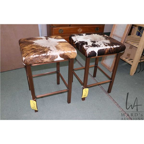 A pair of metal based 26" high stools with calf hide seats