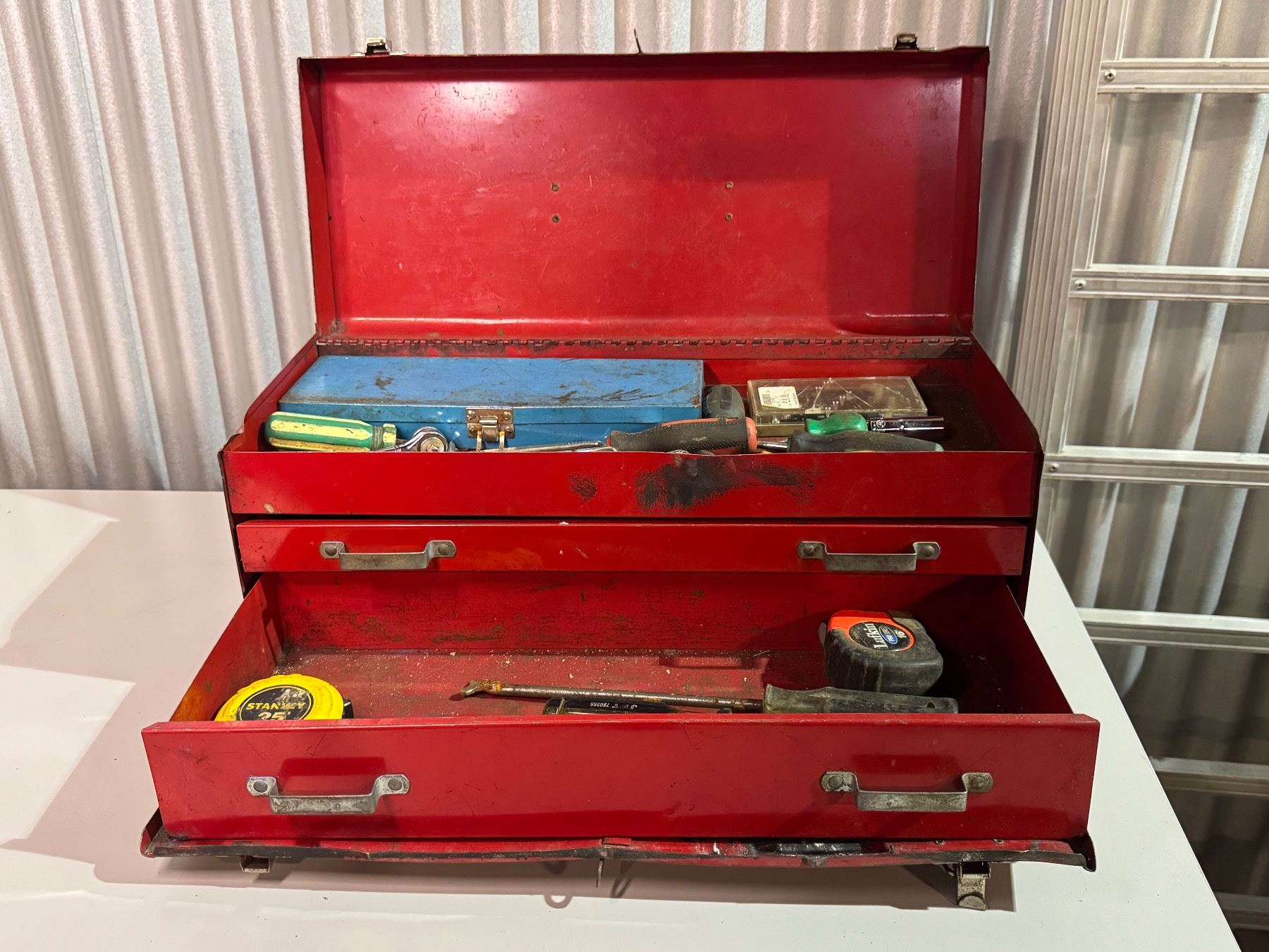 Large red metal tool box with mixed tools