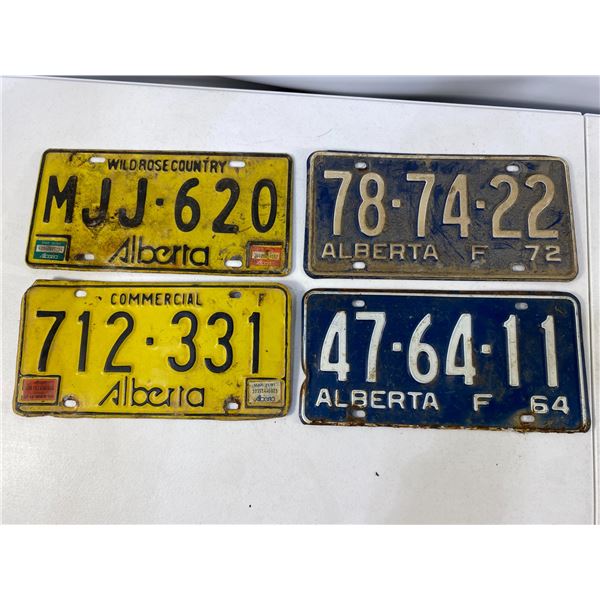 Group of four vintage Alberta license plates including two yellow commercial-style plates with regis