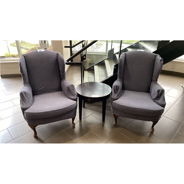 PAIR OF UPHOLSTERED WINGBACK ARM CHAIRS WITH COVERS & DARK WOOD SIDE TABLE