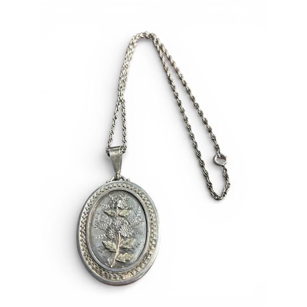 Antique English Sterling silver locket engraved and embellished with flowers in relief suspended on