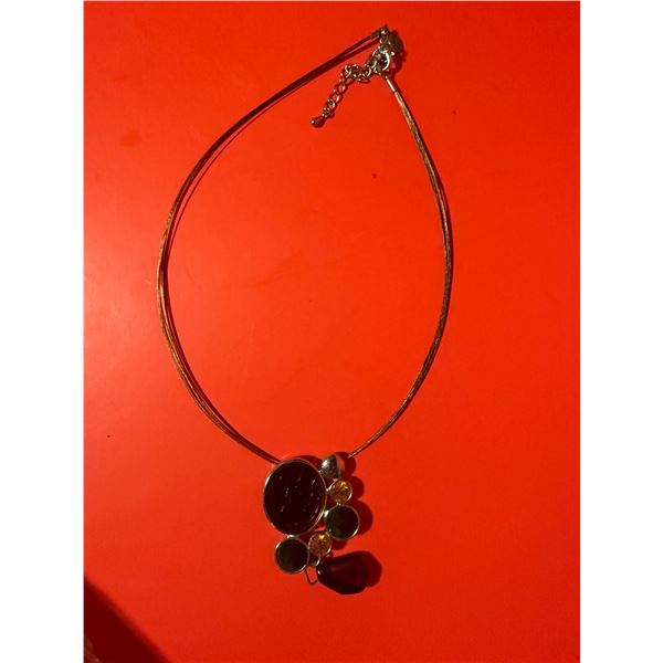 modern metal pendant necklace on a cable chain with a cluster of black and amber-colored accents.