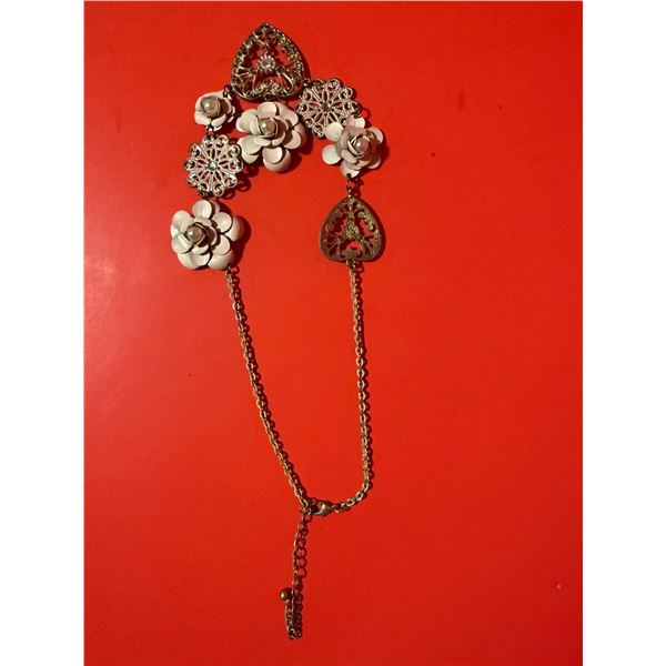 white metal floral brooch with imitation pearl accents and a dangling chain.