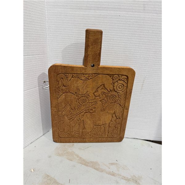 hand-carved wooden cutting or serving board featuring folk-art style animal carvings.