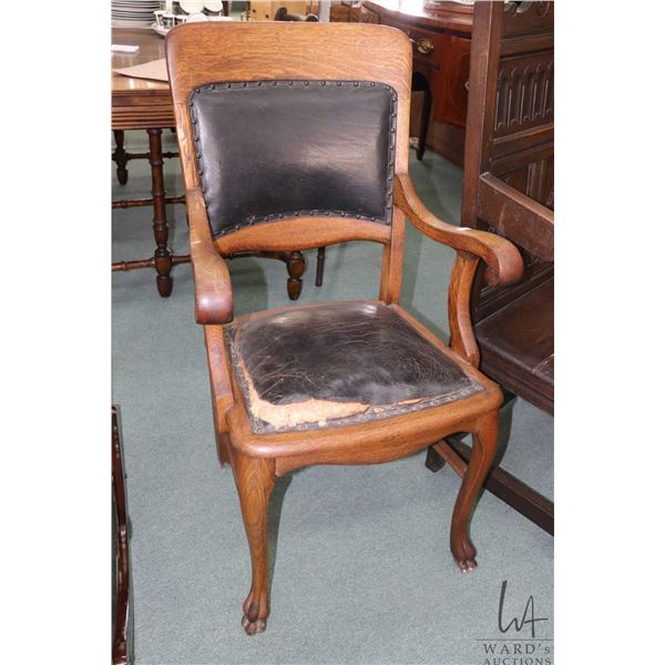 Antique open arm quarter cut oak side chair with leather upholstered seat and back and carved paw fe