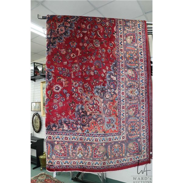 Iranian wool carpet "Mashad" with center medallion on red background and highlights of blues, orange