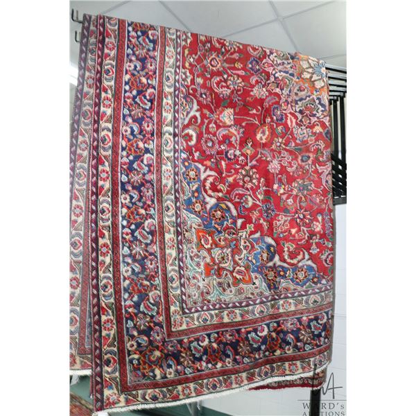 Iranian wool carpet "Mashad" with center medallion on red background and highlights of blues, taupe,