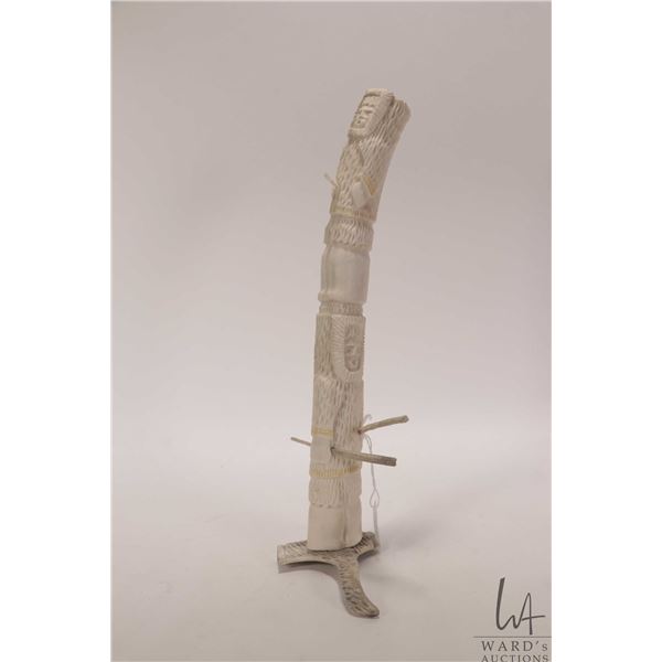 Caribou antler hand carved totem featuring Inuit hunters, 12" in height, signed by artist