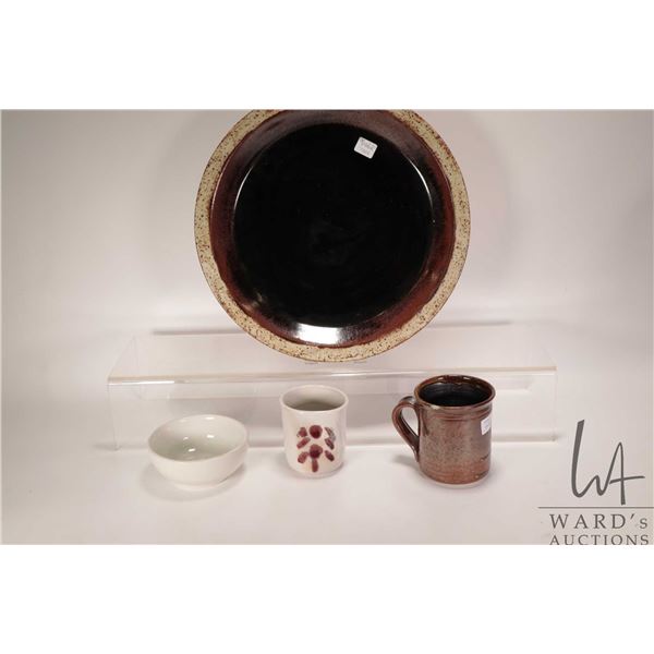 Four pieces of artisan pottery including 14" charger, artist signed mug etc.